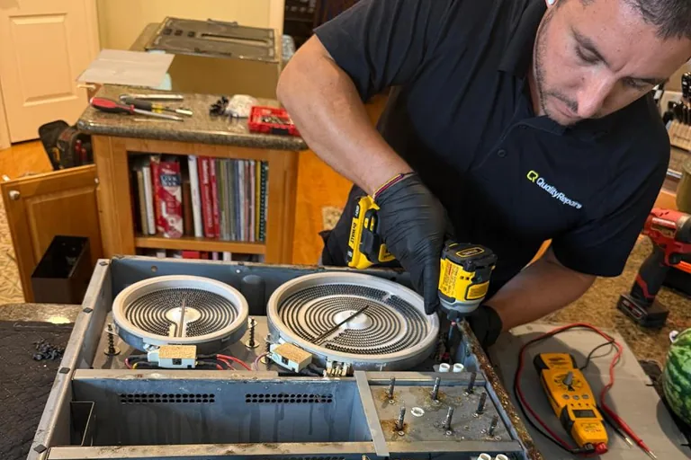 Quality Repairs technician servicing an electric cooktop with the elements exposed