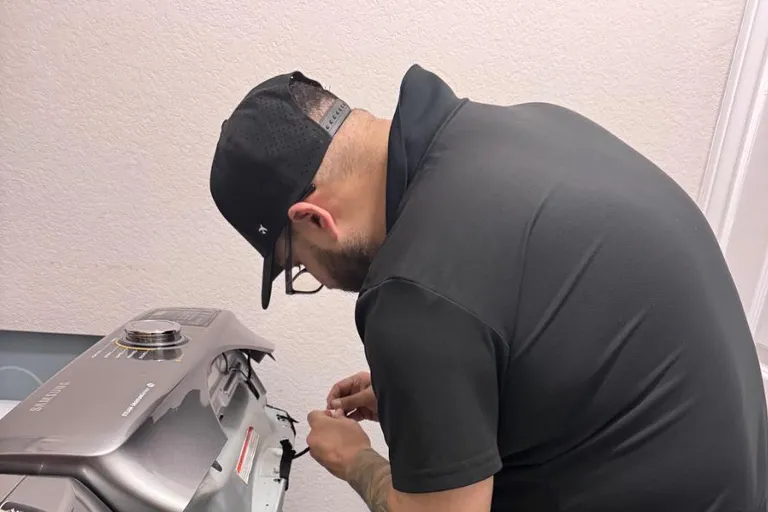 Quality Repairs technician accessing the controls of a top-load washer