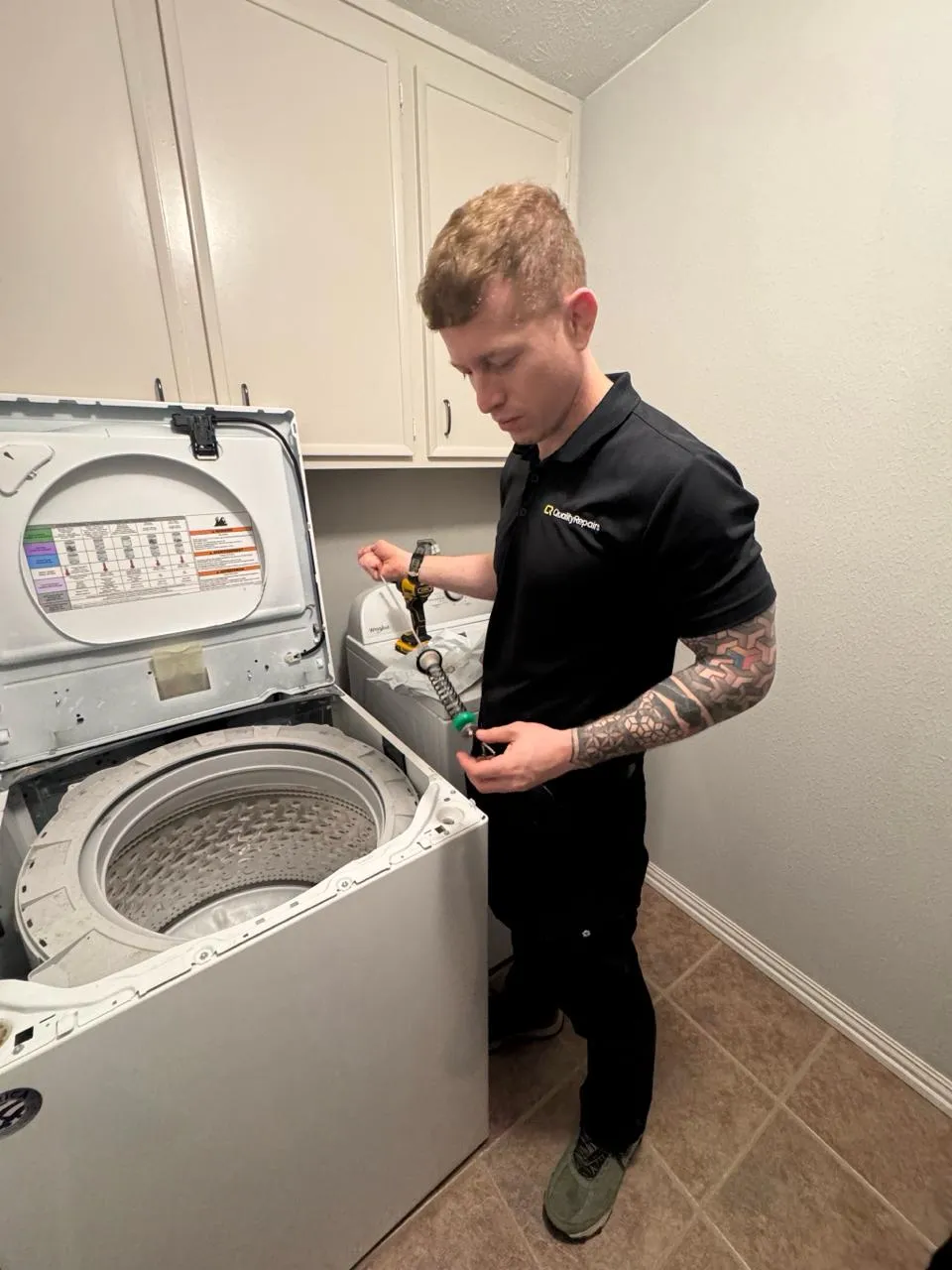 Quality Repairs technician servicing a top-load washer in a local home