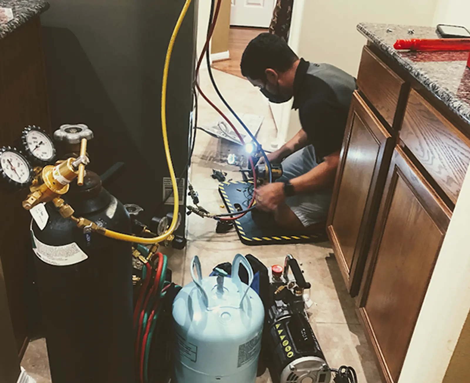 Quality Repairs technician servicing a refrigerator in a local home