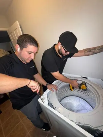 Técnicos de Quality Repairs trabajando en una lavadora